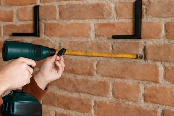Mark and Drill Holes in the Wall To Hang Shelves On Brick Wall